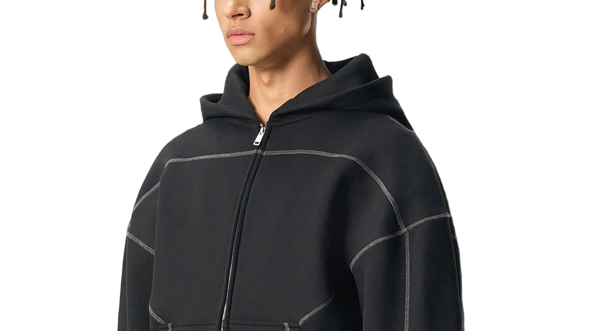 Person wearing a black hoodie with gray accents on a white background